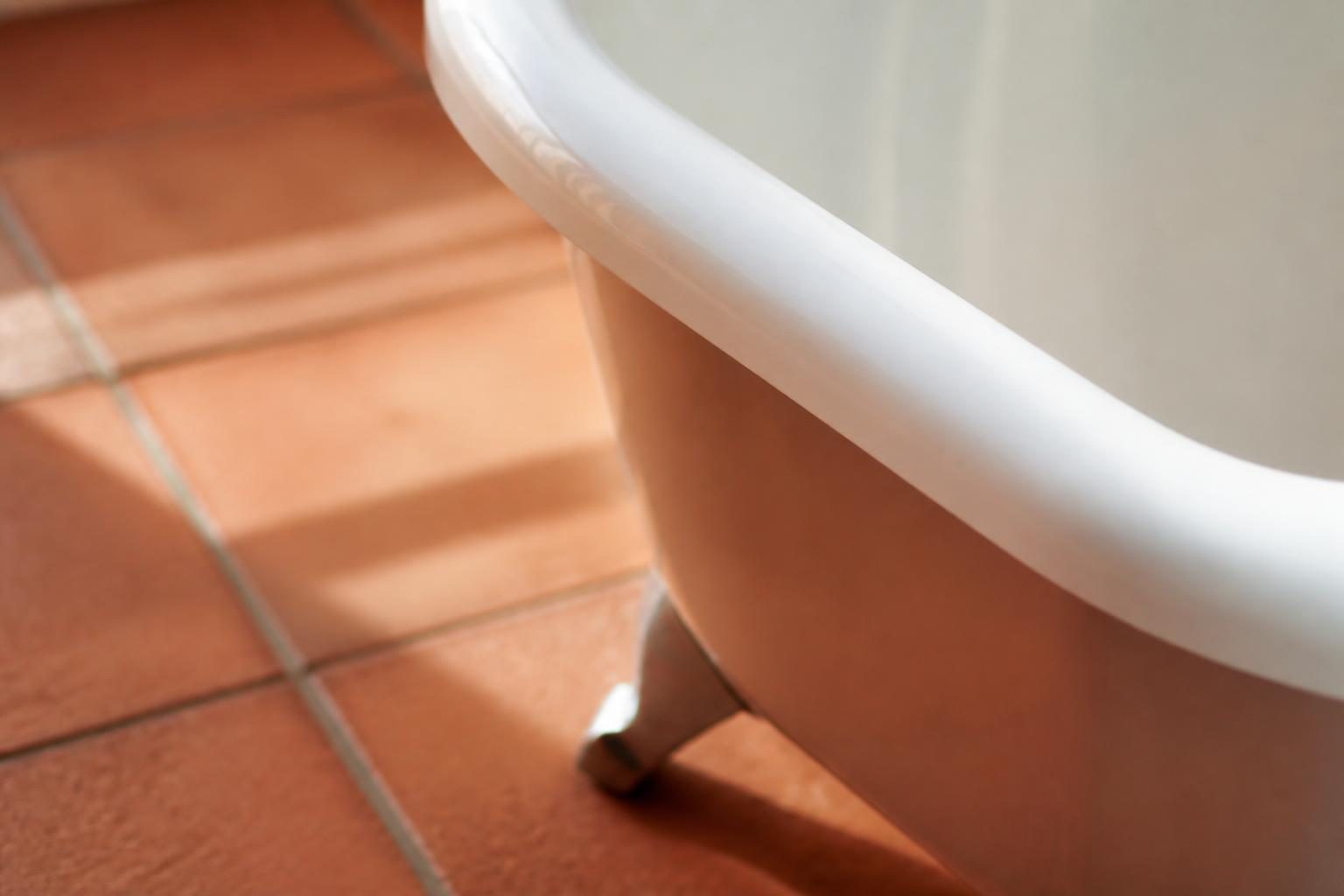 Détail d'un rebord de baignoire avec carrelage et pieds visibles